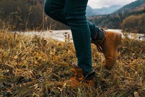 vrouw poten in laarzen en jeans Aan natuur in herfst in de bergen foto
