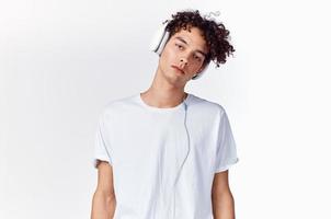 tiener t-shirt en in hoofdtelefoons Aan een licht achtergrond nieuw technologie model- foto