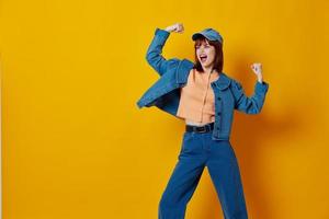 positief jong vrouw in een pet en denim jasje poseren kleur achtergrond ongewijzigd foto