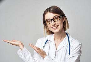 dokter met een stethoscoop shows zijn hand- naar de kant Aan een grijs achtergrond kopiëren ruimte foto