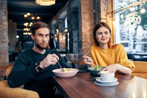 vrolijk jong paar zittend in een restaurant rust uit aan het eten foto