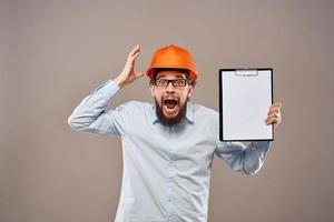 een Mens in een overhemd met een oranje moeilijk hoed ingenieur werk documenten renderen Diensten foto