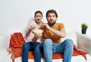 paar in liefde met popcorn en aan het kijken TV terwijl Aan de bankstel binnenshuis foto