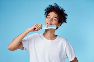 vent model- met een kam in zijn hand- en gekruld haar- blauw achtergrond portret foto