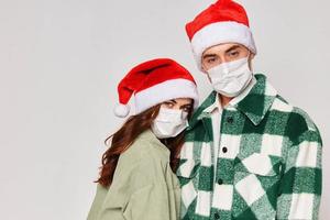 Mens en vrouw in medisch maskers Kerstmis hoeden knuffels bijgesneden studio visie foto