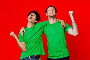 twee vrolijk vrienden knuffel groen t-shirts emoties communicatie rood achtergrond foto