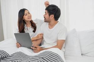 jong gelukkig Aziatisch paar gebruik makend van laptop in bed aan het kijken film, romantisch tijd naar verbeteren familie relatie, familie concept. foto
