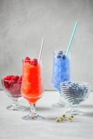 zomer Siciliaans graniet nagerecht, bevroren framboos, bosbes sap in groot glas bril Aan een wit achtergrond. zomer koel, tonic verpletterd ijs cocktail, een soort van sorbet foto