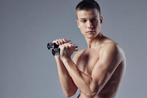 schattig sportief Mens met halters in handen bijgesneden visie gespierd lichaam detailopname foto