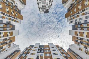 visie omhoog van grond naar blauw lucht tussen wolkenkrabbers, kijken Bij huis van bodem omhoog foto