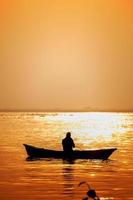 avond gouden zonsondergang tijd, een visser visvangst Aan de kust Aan een boot. foto