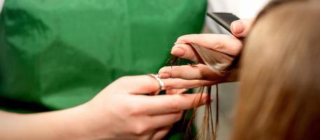 detailopname van een kapper snijdend haar- tips van een vrouw klant in een schoonheid salon. foto