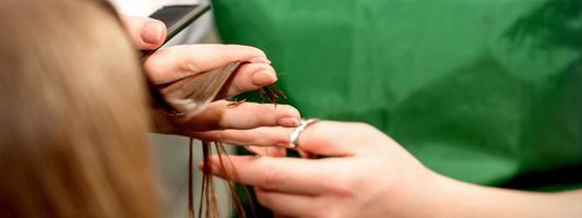 detailopname van een kapper snijdend haar- tips van een vrouw klant in een schoonheid salon. foto