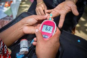 vrouw controle suiker niveau met glucometer gebruik makend van een bloed monster Bij narsingdi, bangladesh. leren naar gebruik een glucosemeter. concept van diabetes behandeling. foto