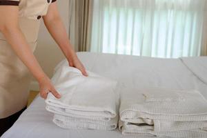jonge meid die handdoek schikt en het bed opmaakt in hotelkamer foto