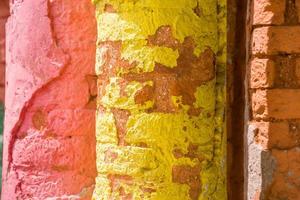 rood, oranje, geel en blauw kleur combinatie oud getextureerde schade muur met kleurrijk bakstenen. foto