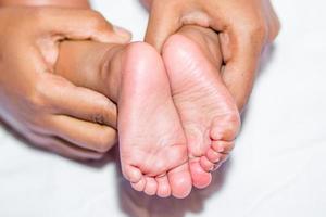 een mam Holding babys twee voeten Aan een wit achtergrond. foto