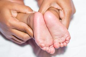 een mam Holding babys twee voeten Aan een wit achtergrond. foto