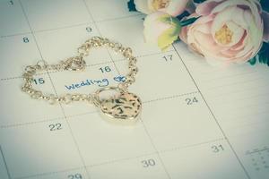 woord bruiloft Aan kalender en goud armband met hart foto