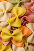 rauw farfalle pasta in verschillend kleuren Aan een donker beton achtergrond foto