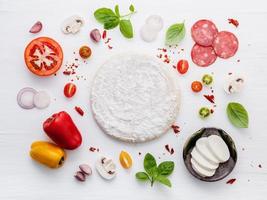 ingrediënten voor zelfgemaakte pizza op witte houten achtergrond foto