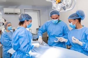 schot in de in werking kamer, assistent handen uit instrumenten naar chirurgen gedurende operatie. chirurgen uitvoeren operatie. professioneel medisch artsen het uitvoeren van chirurgie. foto