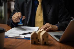 Mens stempelen voorbij gaan aan keurt goed uitverkoop van huis of echt landgoed ondertekening contract foto