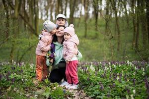 gelukkig moeder dag. wij liefde jij, mama. moeder met een boeket van bloemen en drie kinderen in voorjaar bloeiend Woud. foto