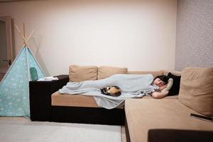 jong vrouw aan het liegen en slaap in bed Bij huis met haar kat. foto