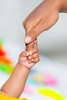 een Aziatisch baby's hand- Holding haar moeder vinger foto