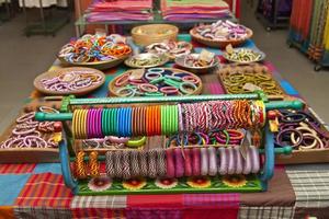 verscheidenheid gekleurde handgemaakt armbanden zijn weergegeven met Aan sommige klein manden voor uitverkoop. foto