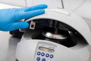 detailopname van een wetenschapper sluitend een klein tafel centrifuge gevulde met buizen. spinnen op kolommen gebaseerd nucleïnezuur zuur Zuivering techniek. diagnose van menselijk papillomavirus virus infectie. foto