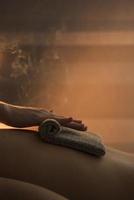 close-up therapeut hand massage van de rug van de vrouw met warme handdoek spa foto