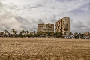 landschap breed zanderig strand in Alicante herfst dag wolken foto