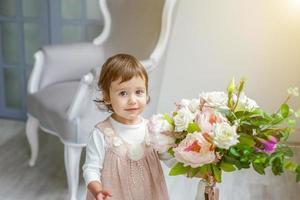 weinig meisje zittend Speel met bloemen boeket foto