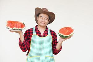 knap Aziatisch Mens draagt hoed, schort, houdt watermeloen fruit naar dienen en Geschenk. concept, landbouw gewassen. Thais boer, toenemen en verkopen watermeloen fruit net zo economisch gewassen. seizoensgebonden fruit foto