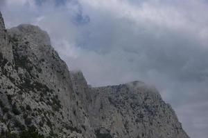 de piek, hoog grijs kliffen tegen de blauw lucht, de Woud Bij de voet van de bergen. berg landschap. foto