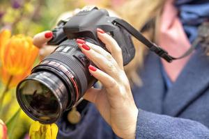 een middelbare leeftijd vrouw fotograaf duurt afbeeldingen van voorjaar bloemen in de botanisch tuin. foto