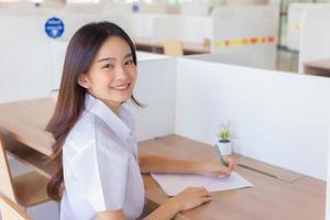 portret van volwassen Thais leerling. schattig Aziatisch jong vrouw leerling in uniform is glimlachen en op zoek Bij camera in de klas Bij Universiteit. foto