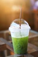 verfrissing met ijs groen thee in plastic glas Aan de tafel met natuurlijk zonlicht in koffie winkel foto