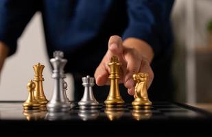 dichtbij omhoog van handen van een bedrijf Mens in beweging koning gouden schaak naar nederlaag tegenstander de schaak spel is ontwikkeling analyse, strategie, en plan, de beheer of leiderschap concept. foto
