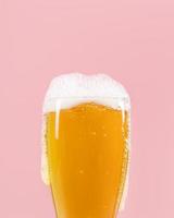 glas met bier en schuim op roze achtergrond