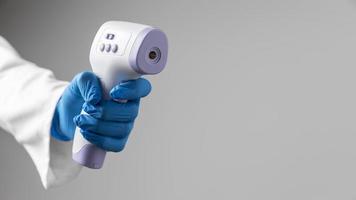 arts in handschoenen houdt thermometer met kopie ruimte foto