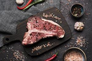 plat leggen van rauwe t-bone steak met peper en zout foto