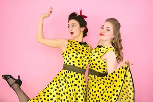 retro meisjes. twee Dames in geel jurken Aan een roze achtergrond. foto