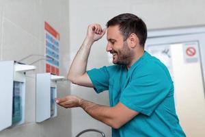 dokter het wassen handen met zeep. mannetje chirurg is voorbereidingen treffen voor chirurgie. hij is in uniform foto