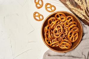 mini gezouten pretzels in een houten kom Aan wit achtergrond. moeilijk crackers of snacks. top visie, bovenstaand foto