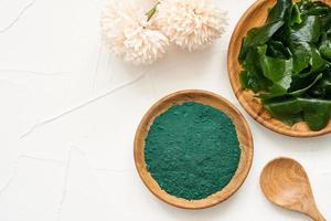 top visie of vlak leggen laminaria of kelp zeewier en spirulina poeder in hout bord en lepel achtergrond. spirulina poeder met konbu en alg voedsel Aan wit tafel achtergrond. foto