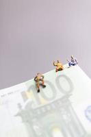 miniatuurmensen, klimmer klimt op een eurobankbiljet, bedrijfsconcept. foto