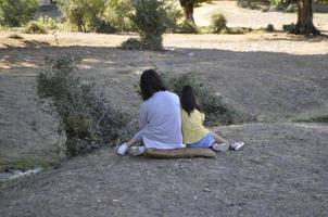 moeder en dochter zittend Aan de gras in een park foto